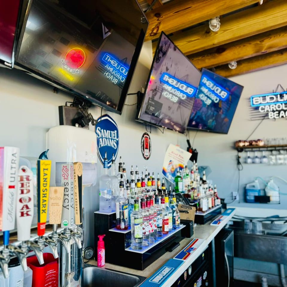 A well-stocked bar at Sunny Daze Smokehouse with beer taps, liquor bottles, and TVs.