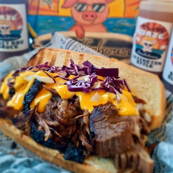 A Sunny Daze Smokehouse BBQ sandwich with pulled pork, melted cheese, and red cabbage.